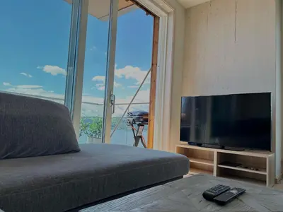 a bedroom with a flat screen tv and a large window at MJOS TOWER - Balcony Suite with lake view in Ringsaker