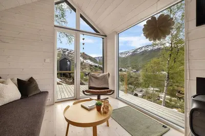 a living room with a chair and a table and large windows at Tiny Mountain Cabin I in Stranda