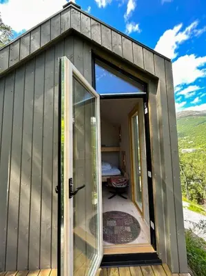 a small gray house with a large glass door at Tiny Mountain Cabin I in Stranda