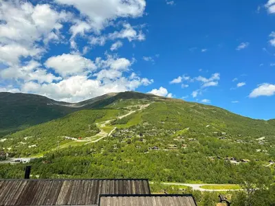 a view of a green mountain with a town at Tiny Mountain Cabin I in Stranda