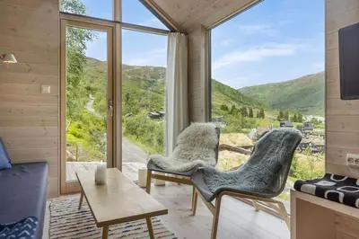 a living room with chairs and a large window at Tiny Mountain Cabin II in Stranda