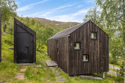 a large wooden barn with a large door at Tiny Mountain Cabin II in Stranda
