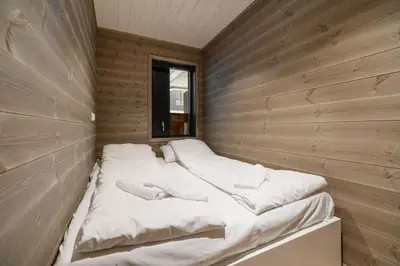 a large white bed in a wooden room at Mountain View Apartment - 102 in Stranda