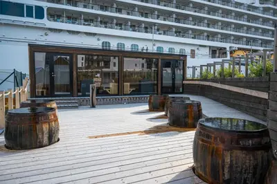 a cruise ship with wooden barrels in front of a building at Sentral leilighet i Brosundet in Ålesund