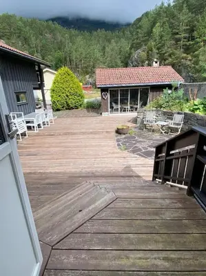 a wooden deck with white chairs and a building at Hus med plass til 7 personer til leie in Veka