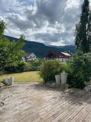 a yard with a wooden deck with plants and houses at Hus med plass til 7 personer til leie in Veka