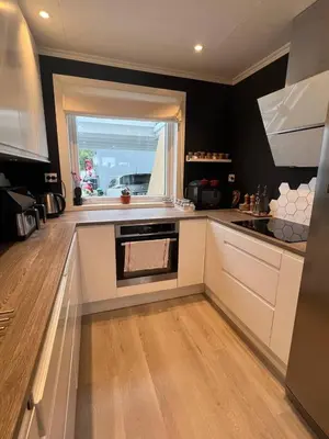 a kitchen with white cabinets and a window in it at Sunny gateaway Room in Lerstad, Suitable for two guests in Ålesund