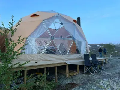 a large tent with a man sitting in it at Handeland Lodge I Arctic Dome in Sauda