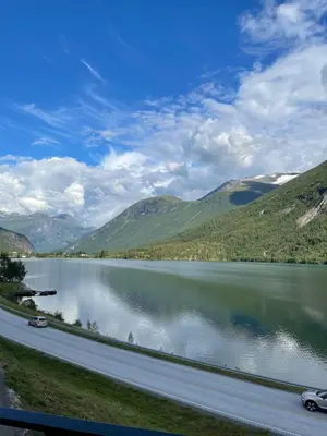 a road next to a lake with mountains at Stryn Golden Resort - Panorama I in Stryn