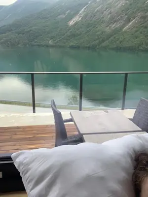a person laying in bed with a view of a lake at Stryn Golden Resort - Panorama II in Stryn
