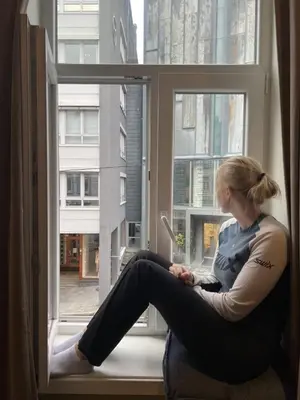 a woman sitting on a window sill looking outside at Ålesund sentrum Parkgata in Ålesund
