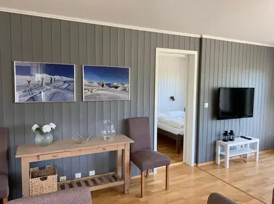 a living room with a table and a bed and a television at Hemsedal, Ski in Ski out, Skarsnuten Panorama 55 in Tuv