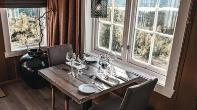 a wooden table with wine glasses on it next to a window at Danebu Kongsgaard - Boutique Hotel in Aurdal