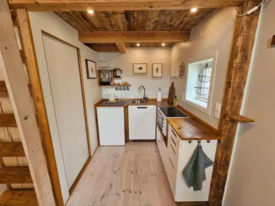 a kitchen with white cabinets and a wooden floor at Sigurd's Tiny House in Vossevangen
