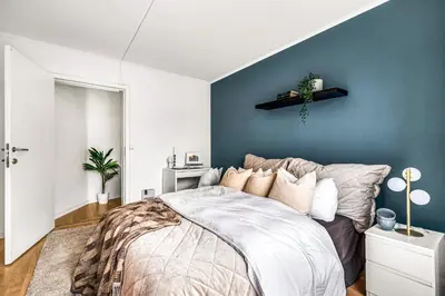 a bedroom with a bed and a blue wall at 3-Bedroom - Heart of Trondheim Center in Trondheim