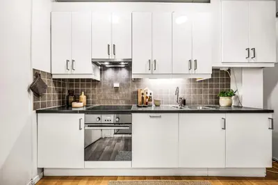 a white kitchen with white cabinets and a sink at 3-Bedroom - Heart of Trondheim Center in Trondheim