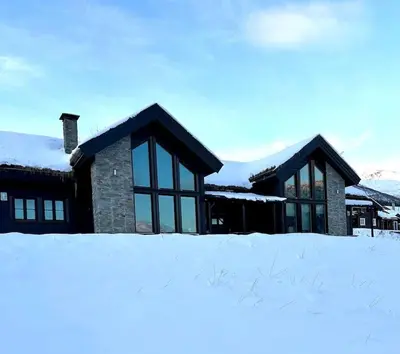a house with snow on the ground in front of it at Myrkdalen Lodge II, luxury family cabin ski in and out in Helgatun