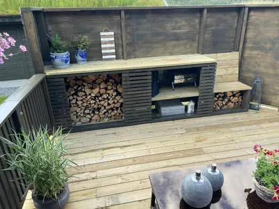 a wooden patio with a fire pit and a table at Modern, lovely holidayhome, in quiet nature close to Trolltunga in Utsikten