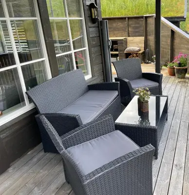 two wicker chairs and a table on a porch at Modern, lovely holidayhome, in quiet nature close to Trolltunga in Utsikten