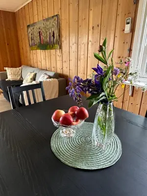 a table with a vase of flowers and fruit on it at Trivelig leilighet med gratis parkering på stedet in Forset