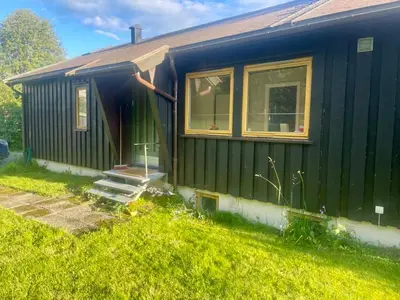a green house with the door open in the grass at Trivelig leilighet med gratis parkering på stedet in Forset