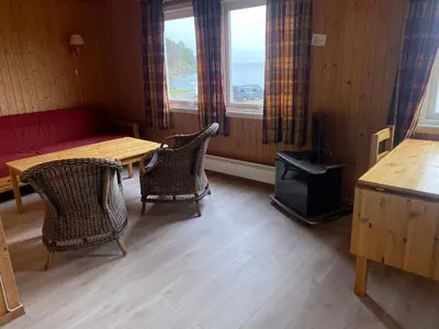 a room with a table and chairs and a stove at Veganeset Camping in Balestrand