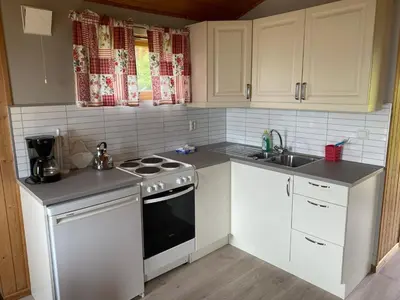 a kitchen with white cabinets and a stove and a sink at Veganeset Camping in Balestrand