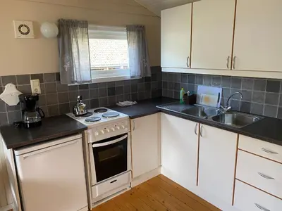 a kitchen with white cabinets and a sink and a stove at Veganeset Camping in Balestrand