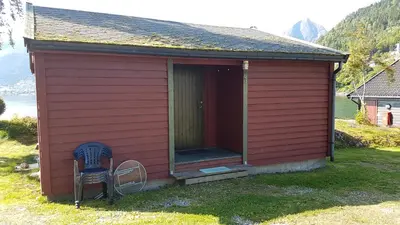 a red house with a chair in front of it at Veganeset Camping in Balestrand