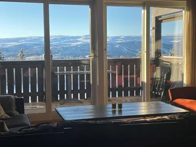 a living room with a table and large windows at Fjellparken 351 in Beitostøl