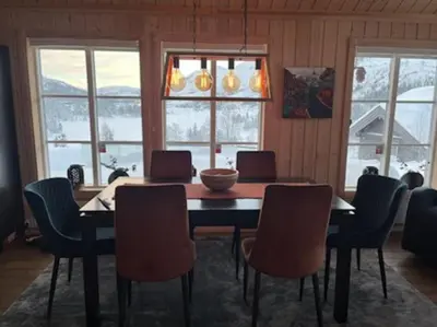 a dining room with a table and chairs and windows at Hytte Gaustablikk in Gaustablikk