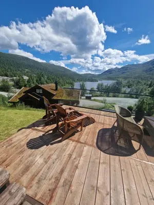 a wooden deck with a picnic table and chairs on it at Hytte Gaustablikk in Gaustablikk