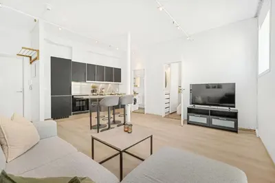 a white living room with a couch and a kitchen at Sentral 2-romsleilighet in Trondheim