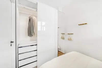 a room with a closet with white walls and a bed at Sentral 2-romsleilighet in Trondheim