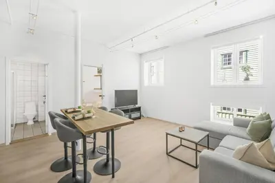 a white living room with a table and a couch at Sentral 2-romsleilighet in Trondheim