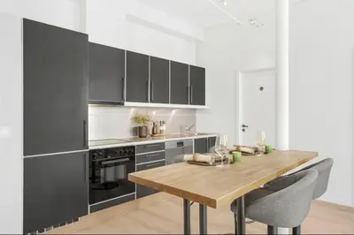 a kitchen with a wooden table and black cabinets at Sentral 2-romsleilighet in Trondheim