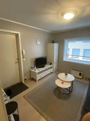 a living room with a table and a tv at Sentralt leilighet in Ålesund