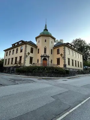 a large white building with a green roof on a street at Flott leilighet in Bergen