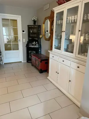 a kitchen with white cabinets and a tiled floor at Flott leilighet in Bergen