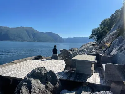 a person sitting on a dock near a body of water at Fjordhus in Austerheim