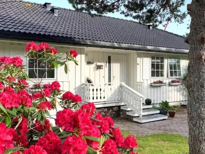a white house with red flowers in front of it at Fjordhus in Austerheim