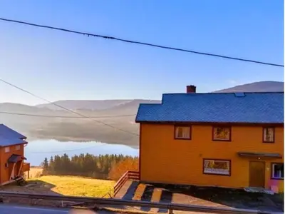 a yellow house with a view of a lake at Knobelauch Family Home, Valdres in Vøle