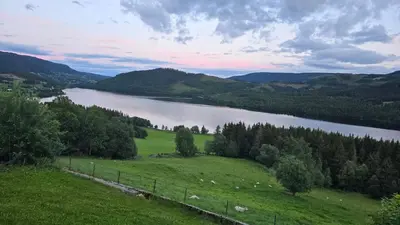 a view of a river and a field with a fence at Knobelauch Family Home, Valdres in Vøle