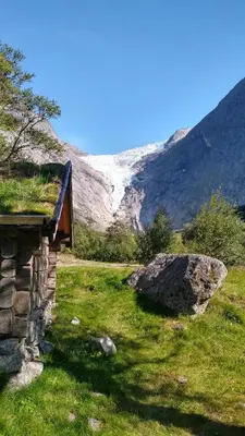 a bench on a field with a mountain in the background at Oldevatn Camping in Olden