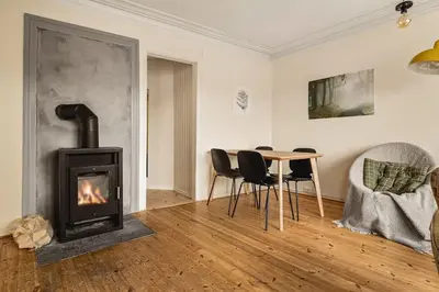 a living room with a fireplace and a table and chairs at Nydelig hus med privat hage og fantastisk utsikt over Fisketorget, Bryggen og Bergen sentrum in Bergen