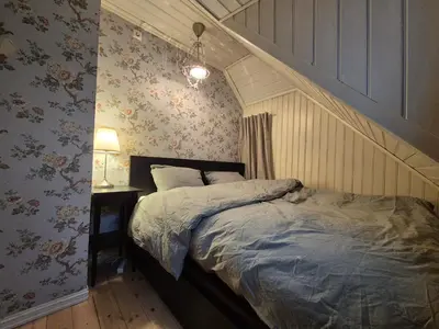 a bedroom with a bed and a wall with flowers at Nydelig hus med privat hage og fantastisk utsikt over Fisketorget, Bryggen og Bergen sentrum in Bergen