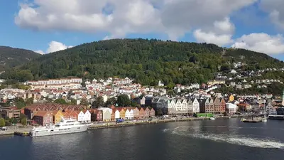a town on a hill next to a body of water at Nydelig hus med privat hage og fantastisk utsikt over Fisketorget, Bryggen og Bergen sentrum in Bergen