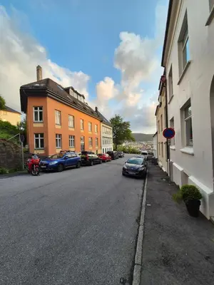 a street with cars parked on the side of the road at Nydelig hus med privat hage og fantastisk utsikt over Fisketorget, Bryggen og Bergen sentrum in Bergen