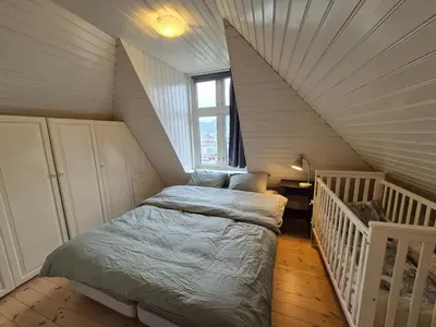 a small bedroom with a bed in a attic at Nydelig hus med privat hage og fantastisk utsikt over Fisketorget, Bryggen og Bergen sentrum in Bergen