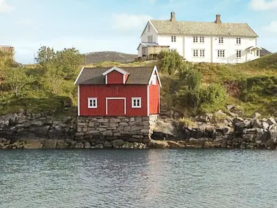 a red house on a hill next to the water at 11 person holiday home in Bud-By Traum in Bud